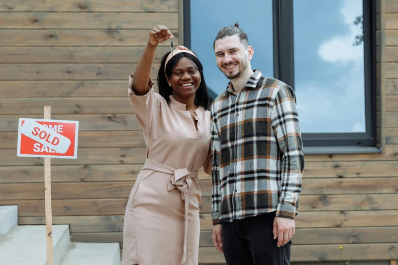 Casal sorrindo em frente ao imóvel próprio conquistado após planejamento financeiro
